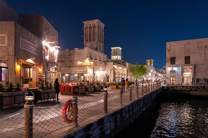 Wind towers and warmly lit lanes along the Al Seef waterfront