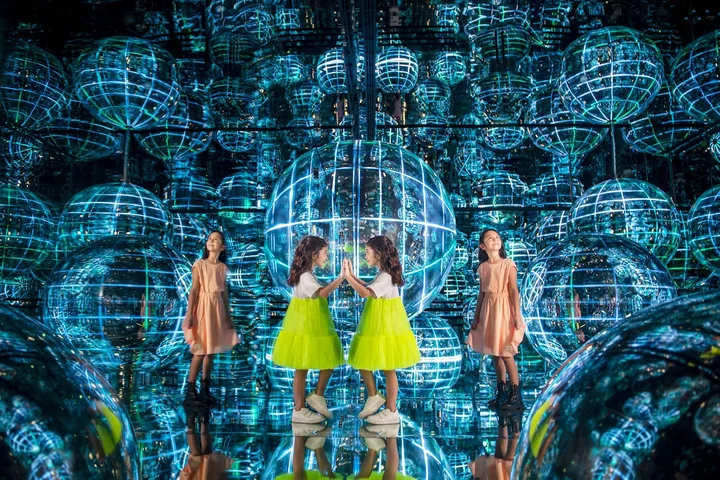 Visitors surrounded by luminous spheres and reflections at AYA Universe