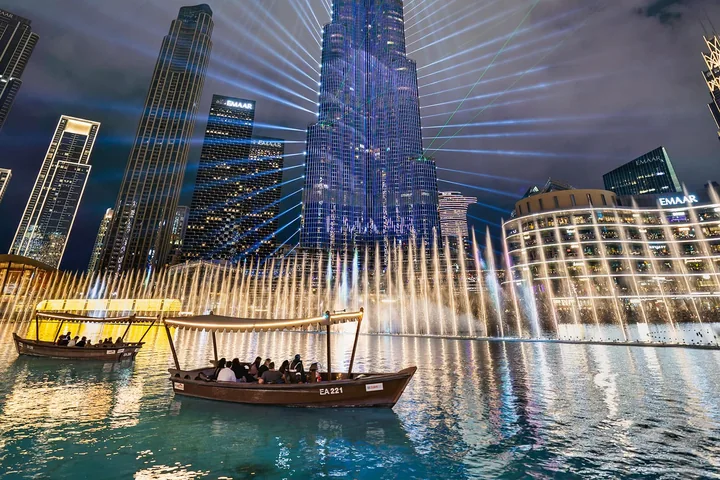 The Dubai Fountain illuminated at night beneath the Burj Khalifa