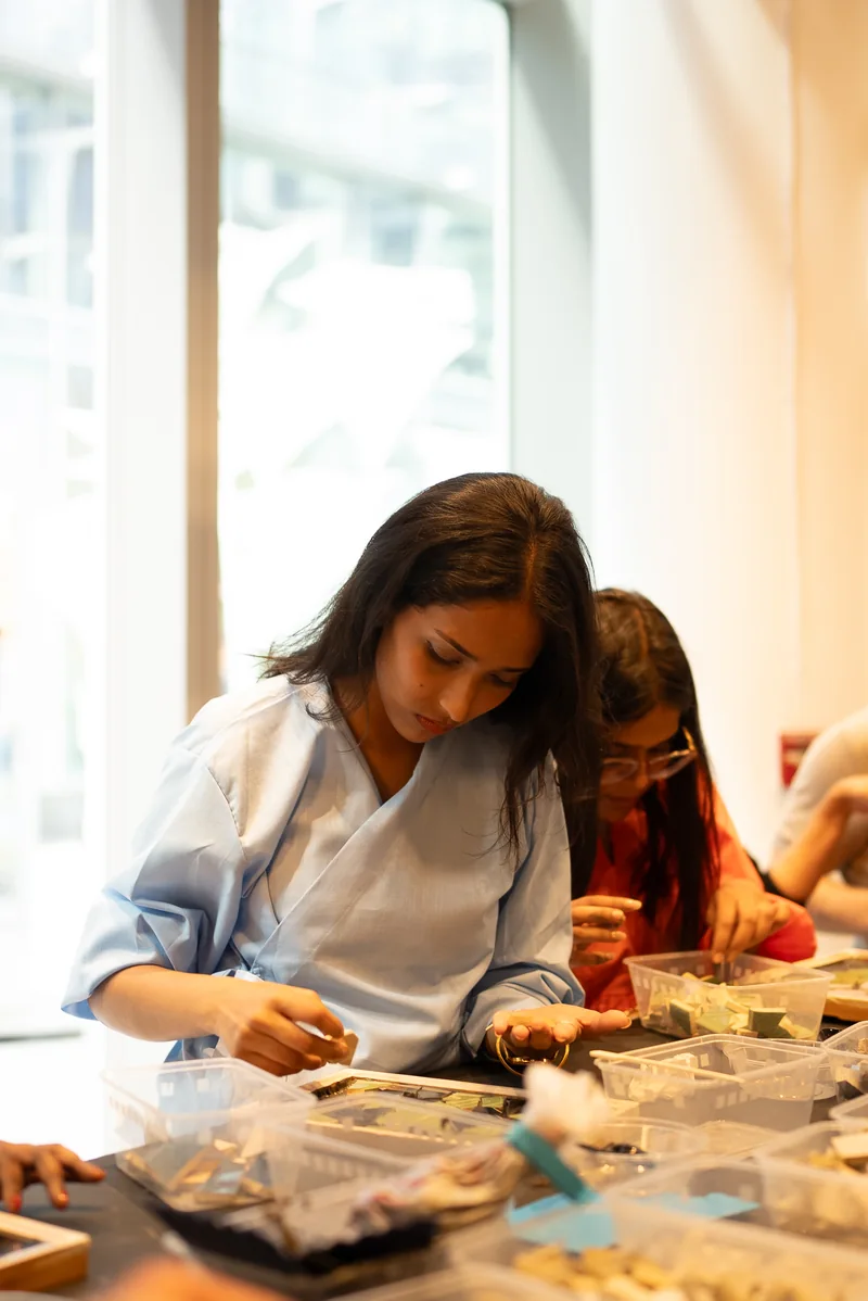 A Design Safari participant making a small object at a workshop table during the 2025 visit